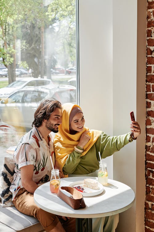 Free Woman Wearing Yellow Hijab Taking Selfie with a Man Stock Photo