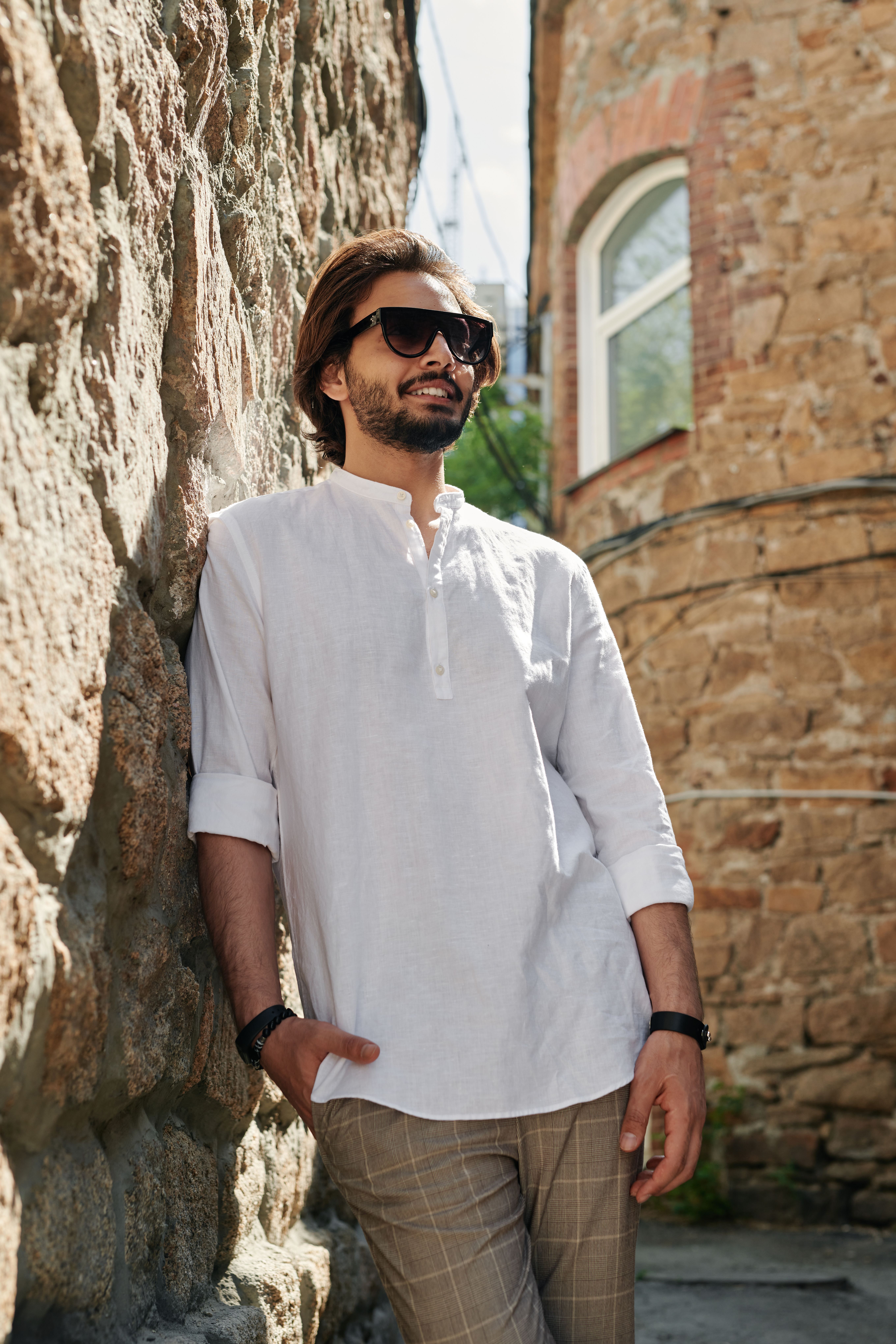 Man Wearing Sunglasses Leaning Against a Stone Wall · Free Stock Photo