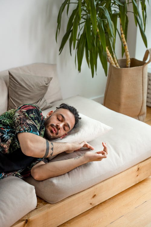Free Man in Leaves Shirt Lying on Bed Stock Photo