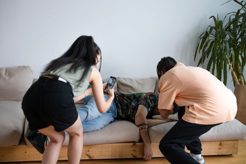 Free Group of friends playfully teasing on a living room couch, capturing casual moments. Stock Photo