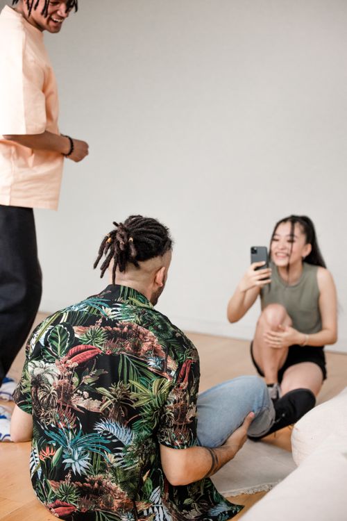 Free Young adults having fun creating content indoors, capturing moments with a smartphone. Stock Photo