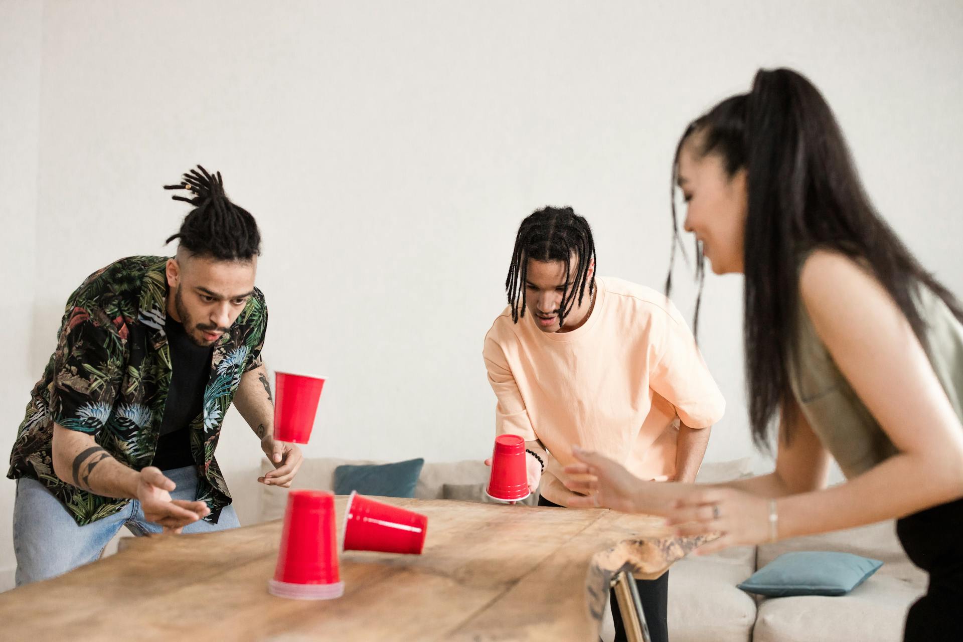 Group of friends enjoying a flipping cup game indoors showcasing fun and engagement.