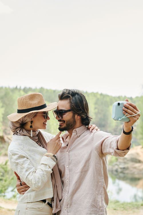Free A cheerful couple taking a selfie outdoors, capturing their happy moments in a scenic setting. Stock Photo