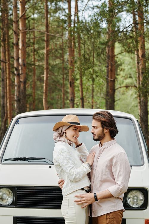 Free A loving couple embraces in front of a vintage van amidst a serene forest setting. Stock Photo