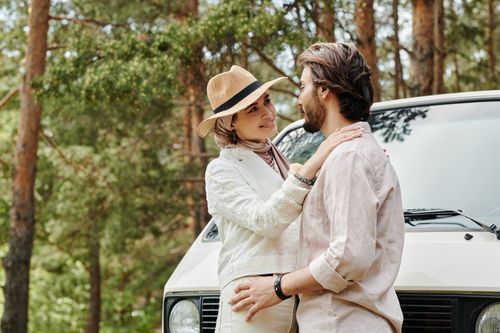 Free A couple standing close in a forest near a parked van, expressing love and affection. Stock Photo