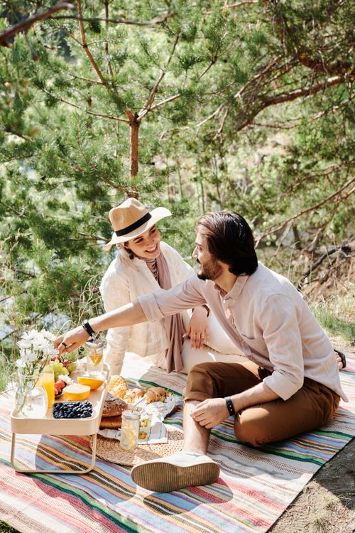 Free A couple enjoys a serene picnic surrounded by lush greenery and sunshine. Stock Photo