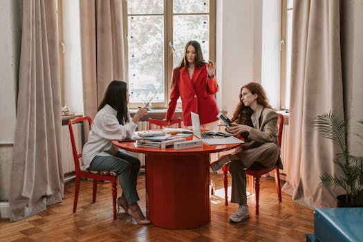 Three women discussing work at a stylish office table. Bright, engaging interior.