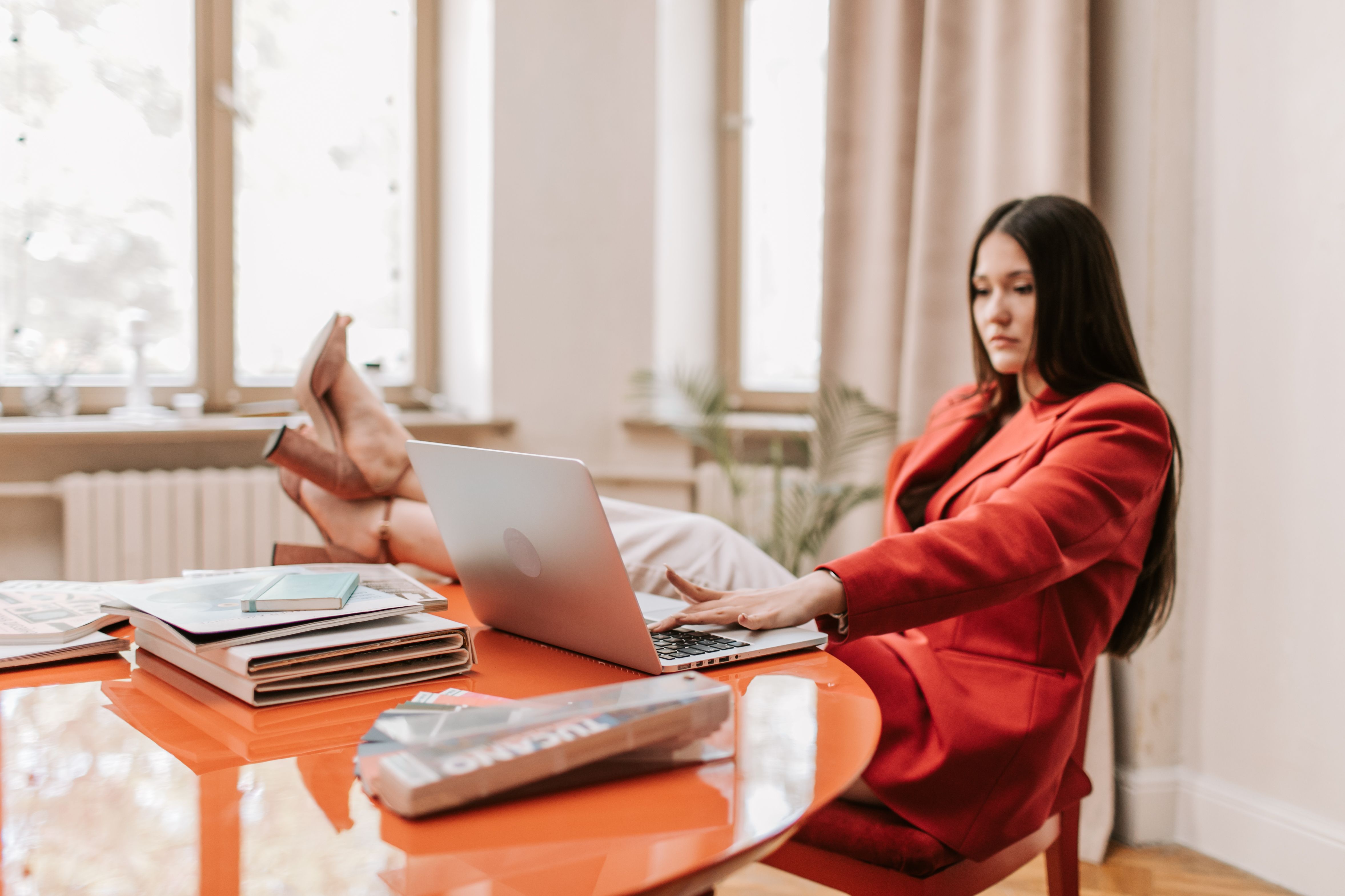 Woman Sitting on a Chair while Raising Her Legs on the Table Working on ...