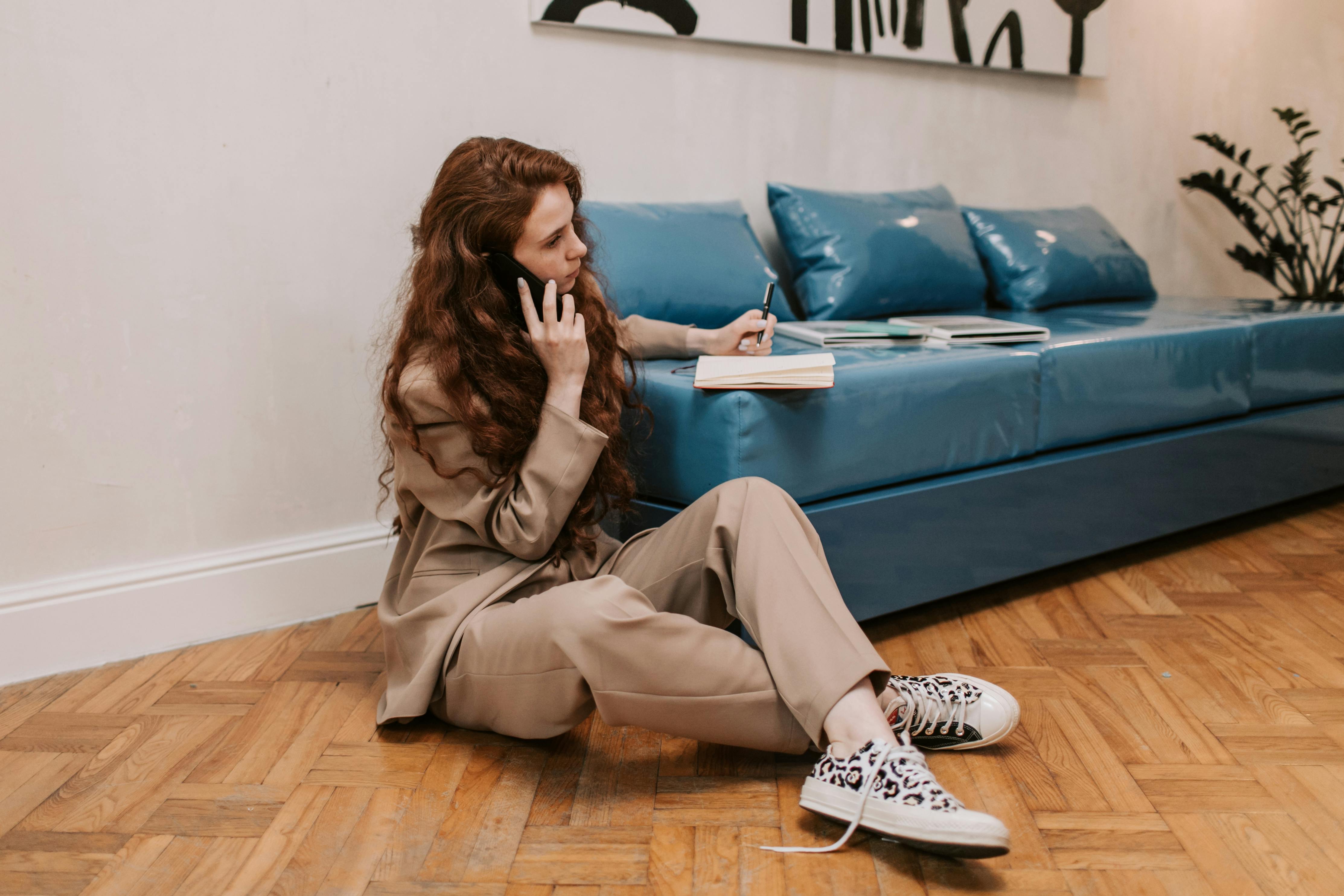 woman writing down notes while having a phone call