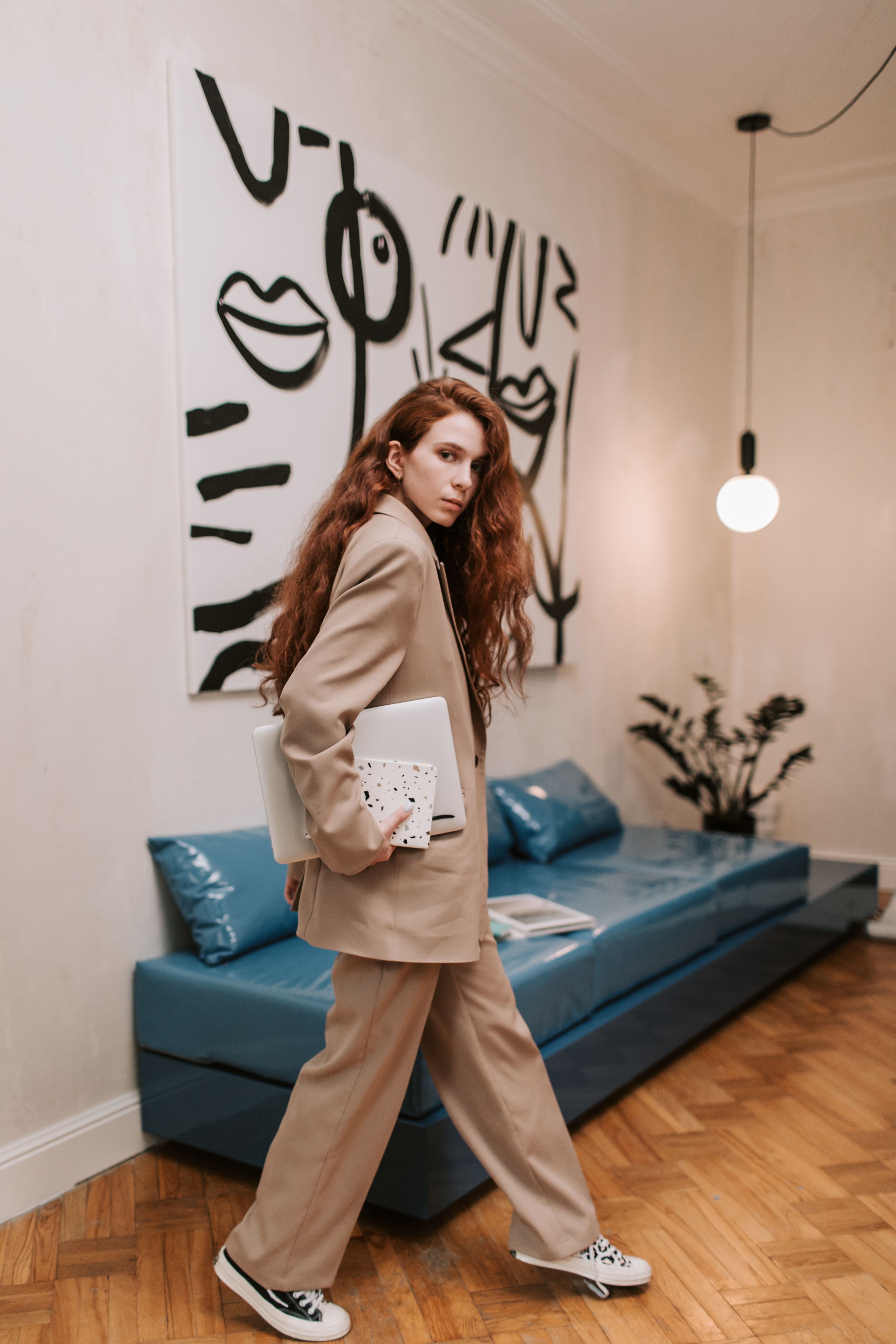 Woman in Brown Coat Standing beside Blue Couch · Free Stock Photo
