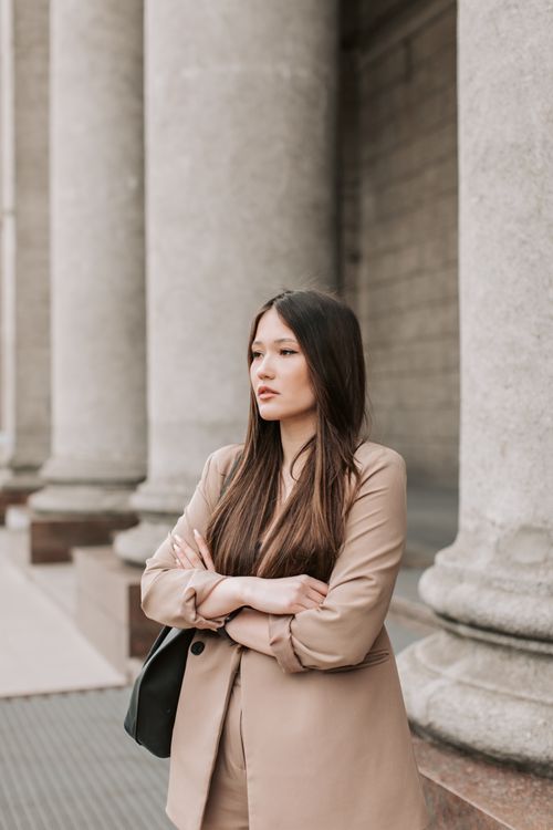 Free Portrait of a confident woman standing with arms crossed near concrete columns. Stock Photo