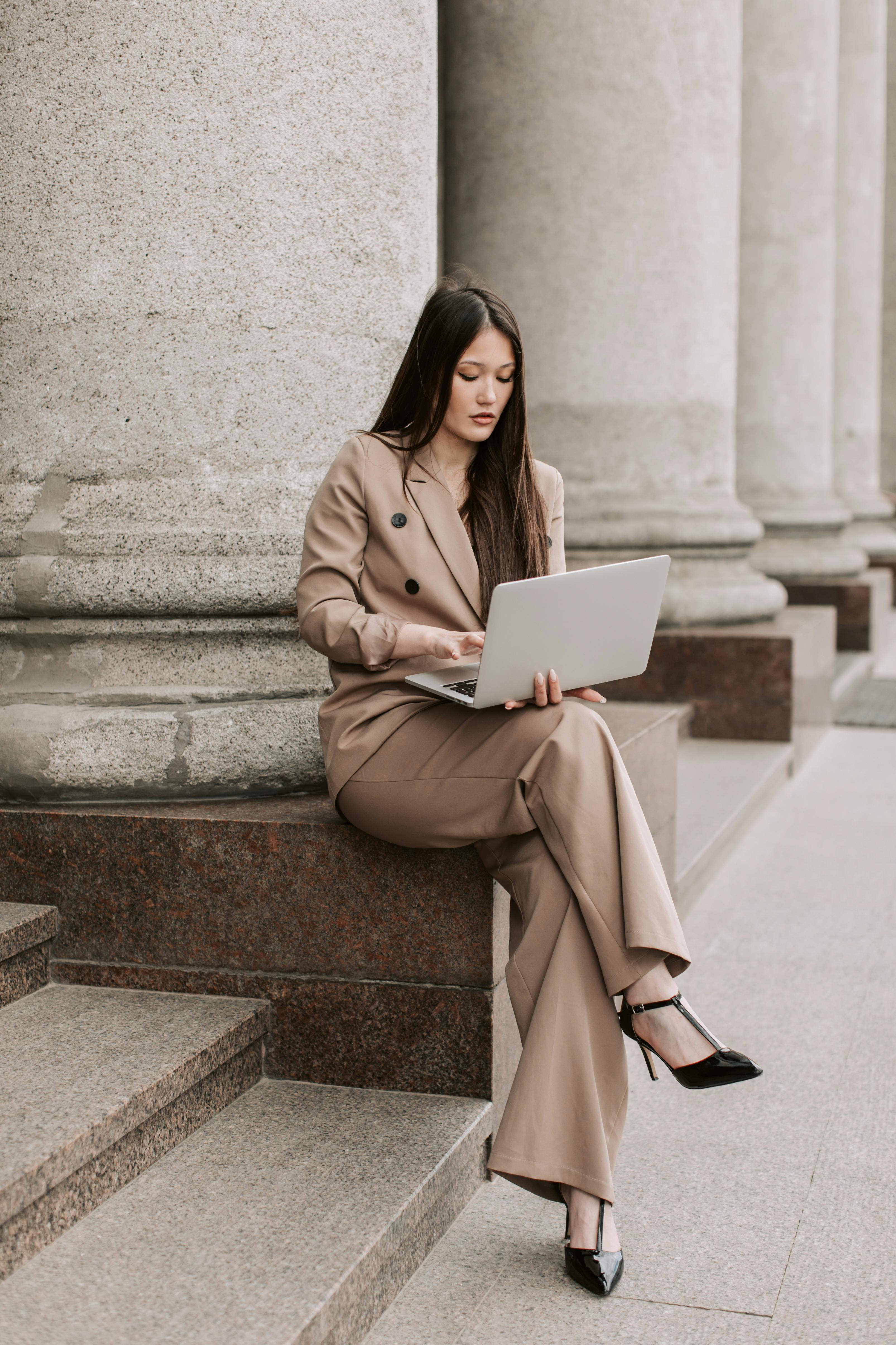 a woman working outside while using a laptop