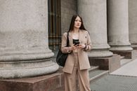 Woman in Brown Coat Standing on Gray Concrete Staircase