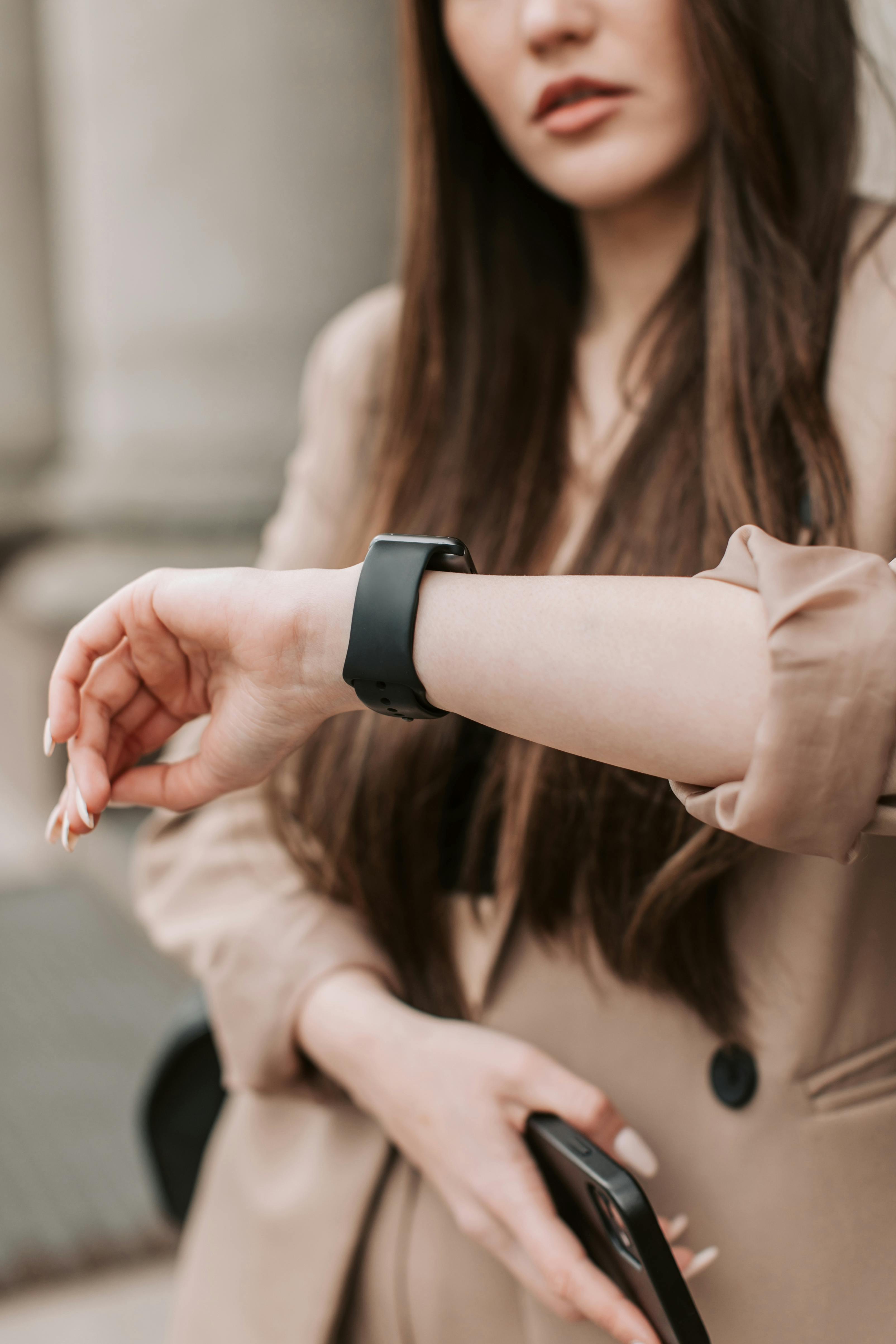 woman in beige blazer looking at the time on her wristwatch