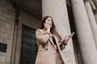 Woman in Brown Coat Holding Smartphone