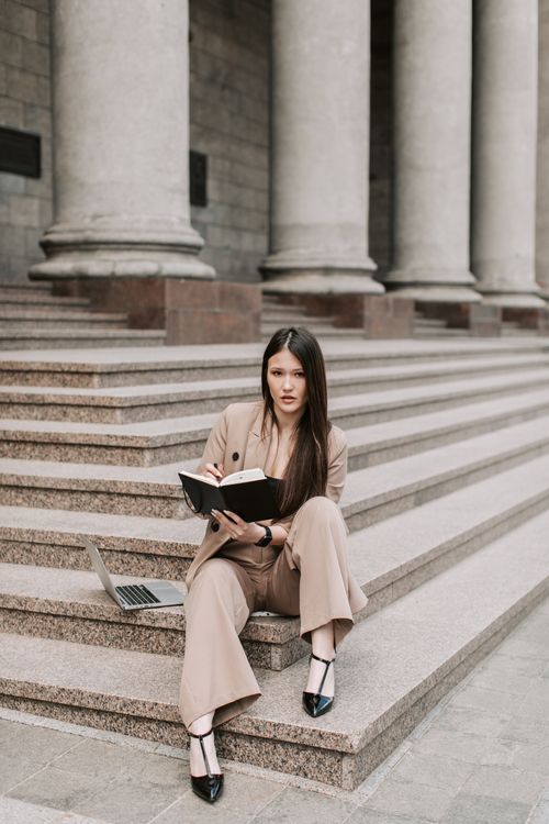 Free Confident woman working on laptop while seated on stone steps, showcasing productivity and focus. Stock Photo