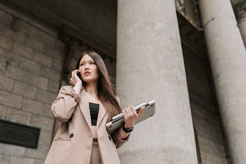 A Woman Talking on the Phone while Carrying Her Laptop