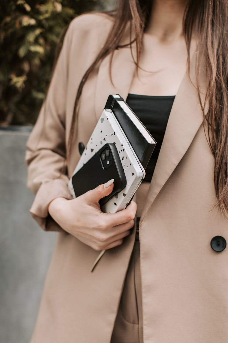 A Person Wearing A Blazer While Carrying Notebooks And Mobile Phone