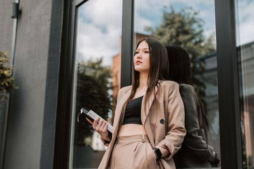 Stylish woman in brown suit posing confidently by a modern window.