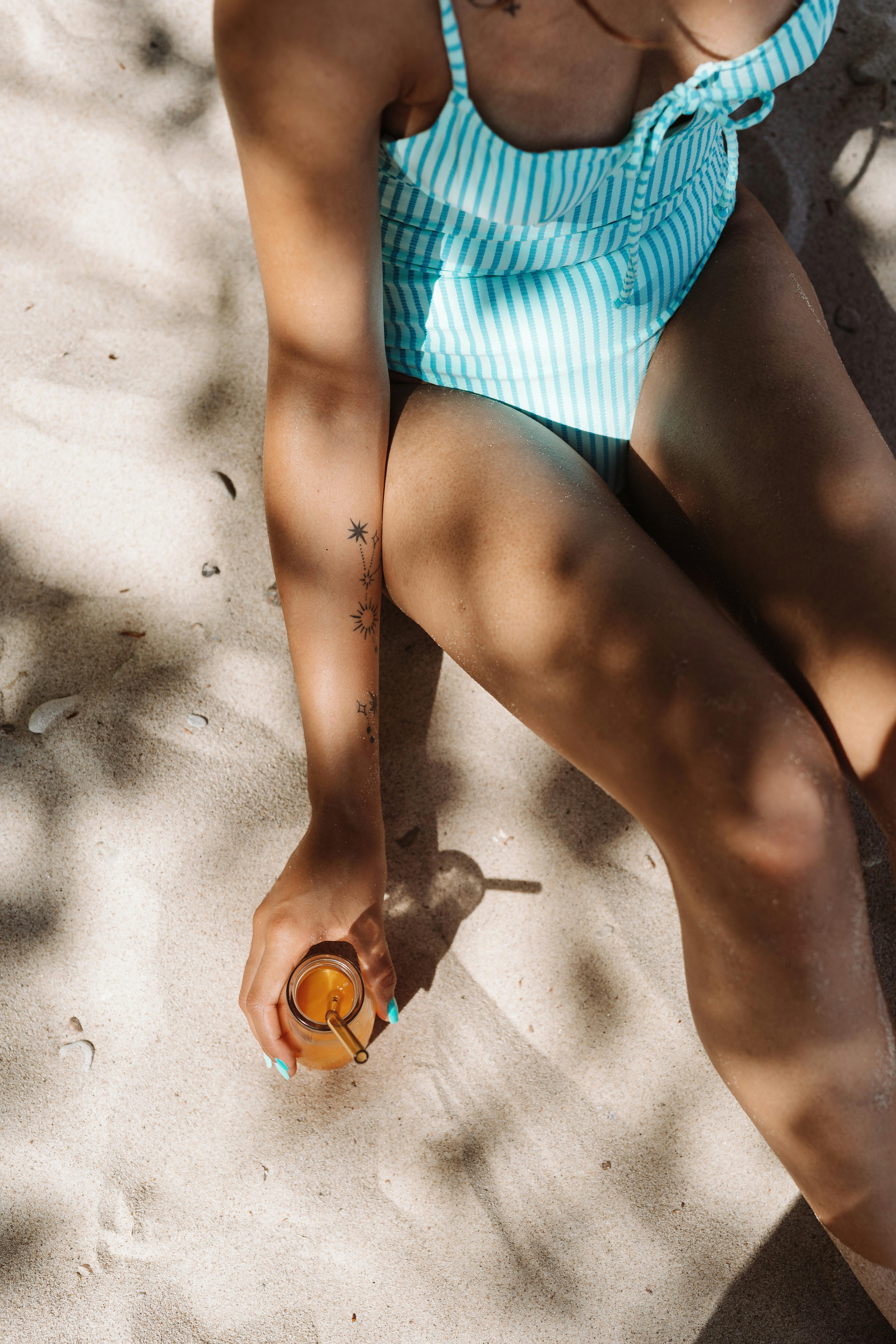 woman in blue and white striped swimsuit holding orange juice