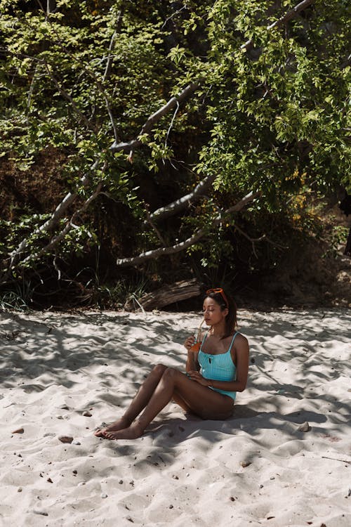 Woman in Blue Bikini Sitting on White Sand