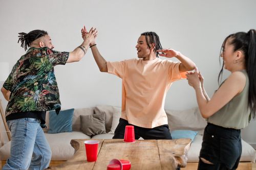 Free Group of diverse friends playing a fun game indoors, celebrating and high-fiving. Stock Photo
