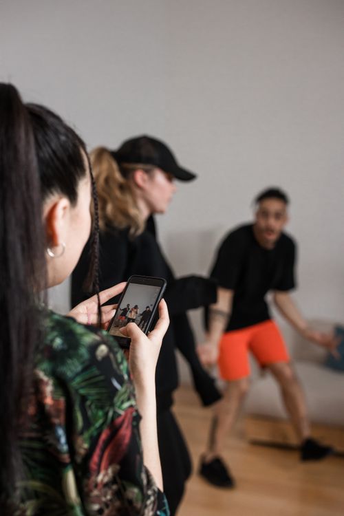 Free A woman captures energetic dance moves on her smartphone indoors. Stock Photo