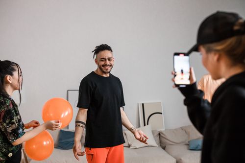 Free A group of friends filming a playful TikTok dance video indoors, capturing joy and creativity. Stock Photo