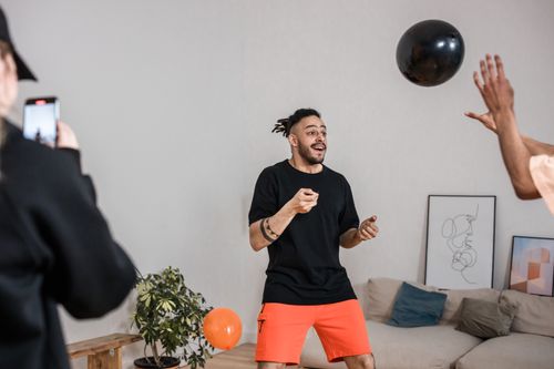 Free A group of adults joyfully playing with balloons indoors, capturing a lively moment. Stock Photo