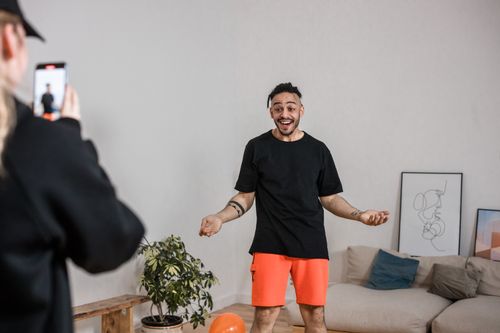 Free Man in black shirt vlogging indoors with smartphone capturing lively expressions. Stock Photo