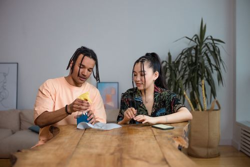 Free Two young adults converse at a table, focusing on teamwork and interaction inside a modern setting. Stock Photo