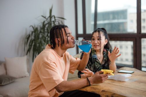 Free African American man and Asian woman enjoying a casual drink together indoors. Stock Photo