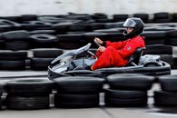 A focused go-kart racer in action on an outdoor track, showcasing speed and agility.