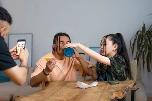Free Friends having fun and filming a drinking challenge indoors, capturing moments of laughter and creativity. Stock Photo