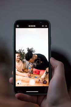 A close-up of a handheld smartphone displaying a candid photo of two people indoors.