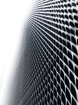 Monochrome abstract photo of a geometric metal mesh pattern with dramatic lighting.