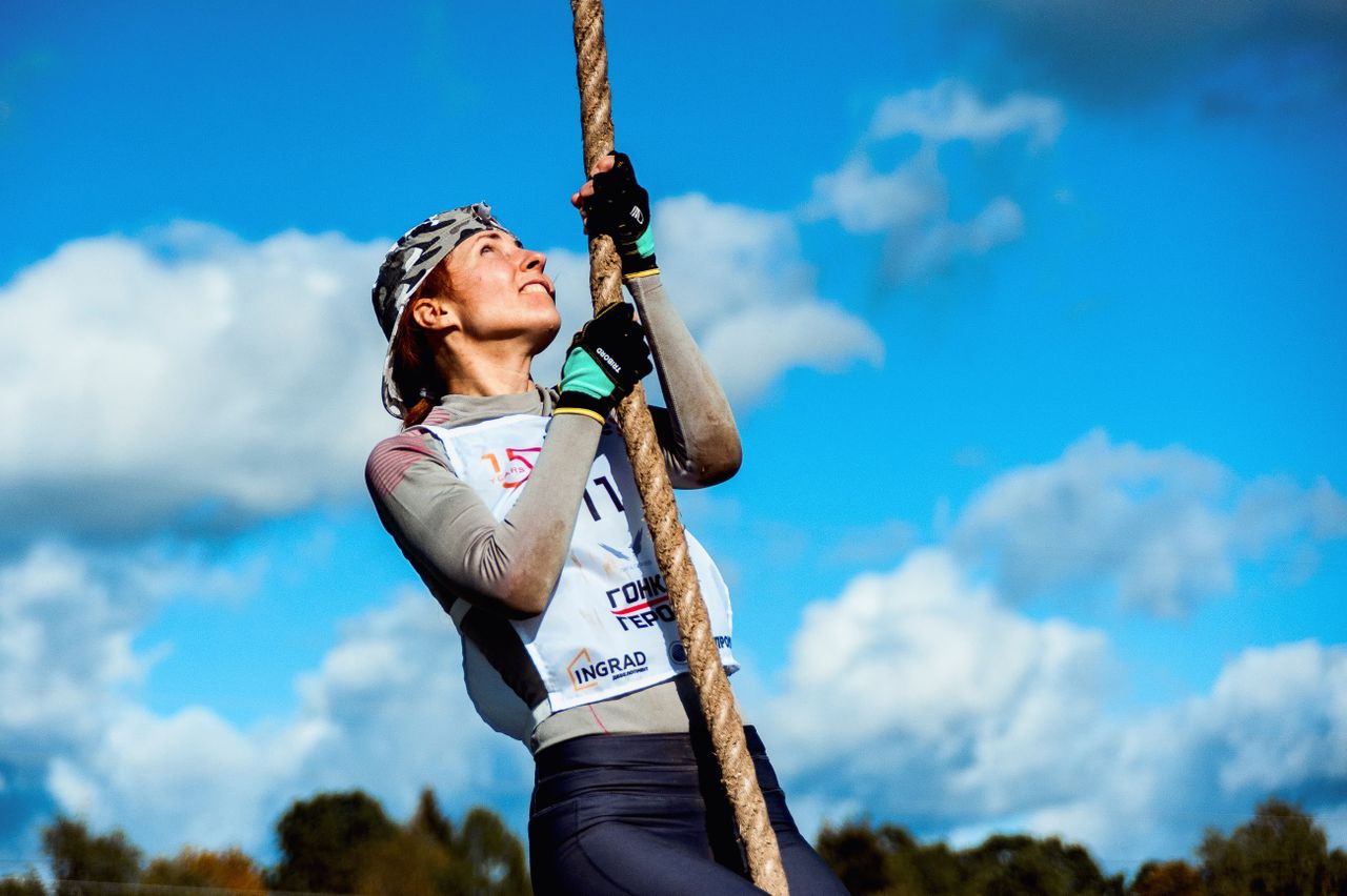 female athlete climbs rope against a bright blue sky perfect for sport