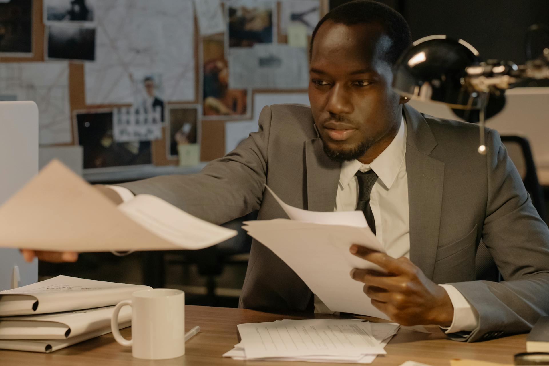 Man in a business suit working with documents at a desk in an office setting.