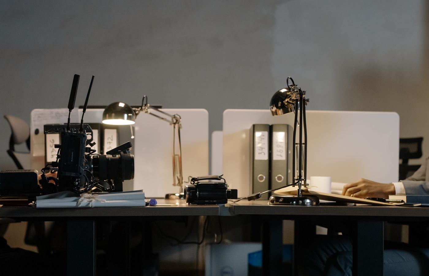 A contemporary office setup featuring desks with lamps, a camera, and divided workspace layout.