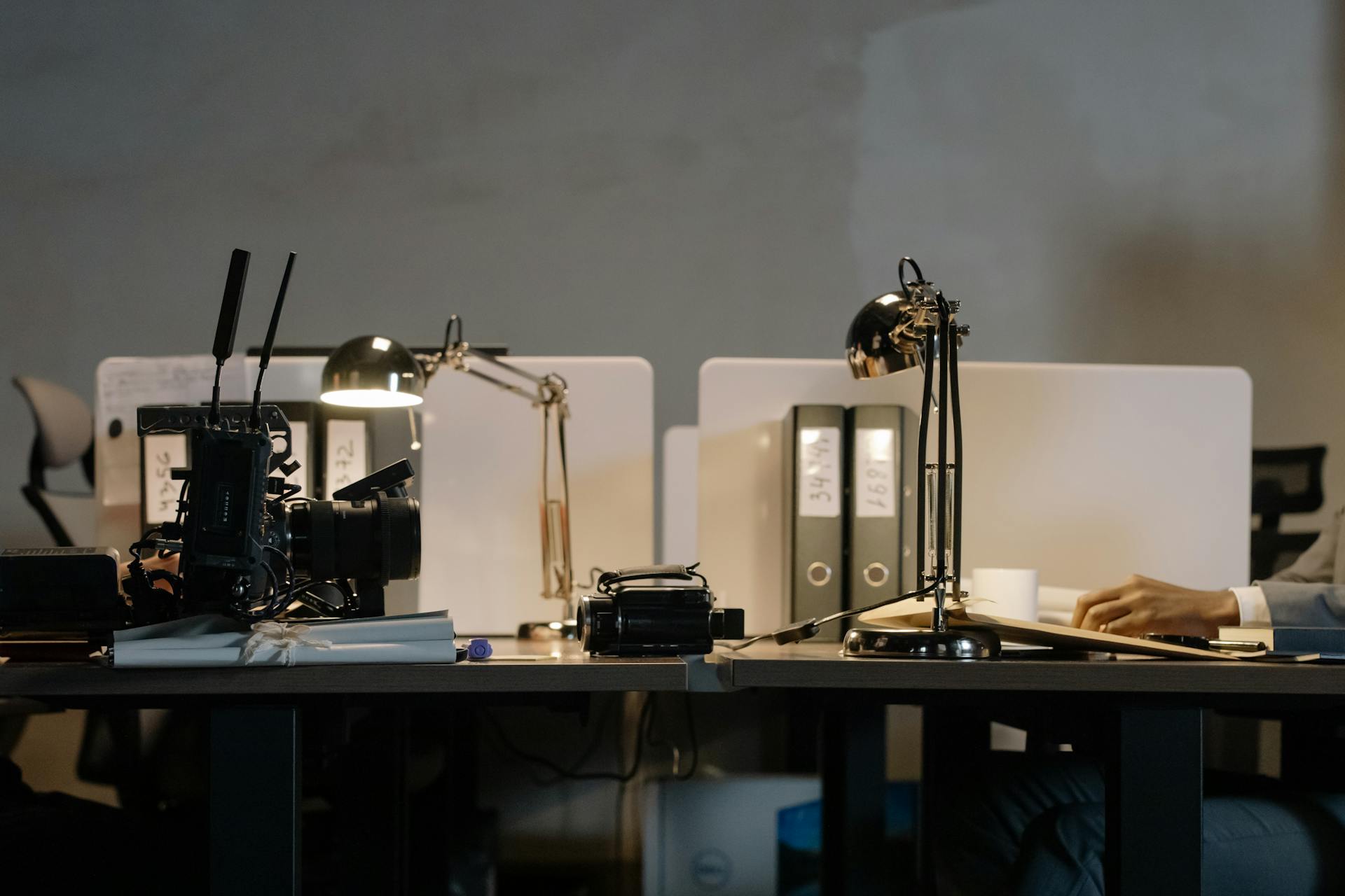 A contemporary office setup featuring desks with lamps, a camera, and divided workspace layout.