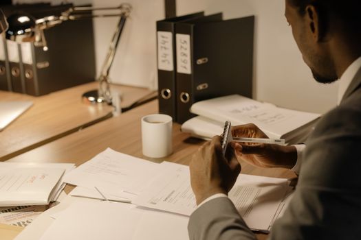Man in gray suit reviewing documents at an organized workspace.