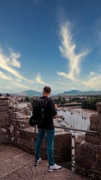 A man with a backpack enjoys the breathtaking view from Conwy Castle, Wales.