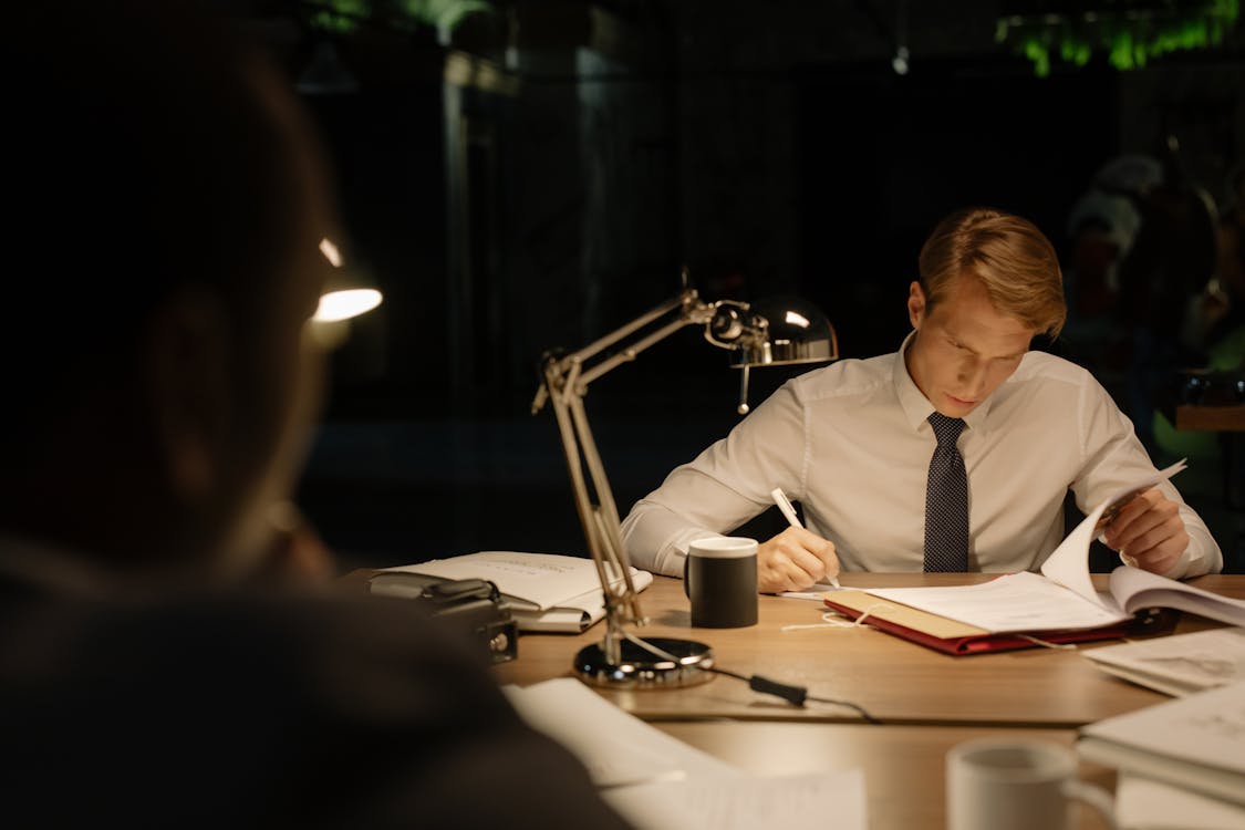 Private Investigator in White Dress Shirt Reading Documents on a Desk