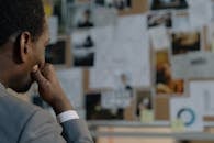 Man in Gray Jacket Looking at the Items on the Wall
