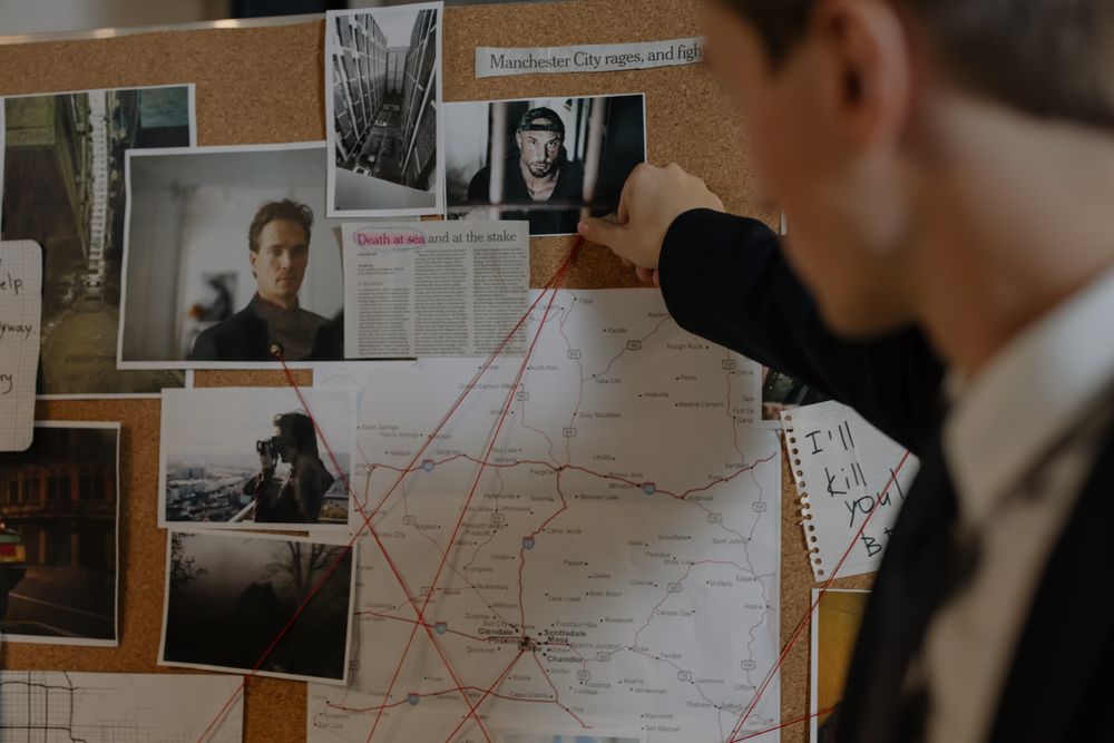 Investigator working through photographs and notes pinned to a case board