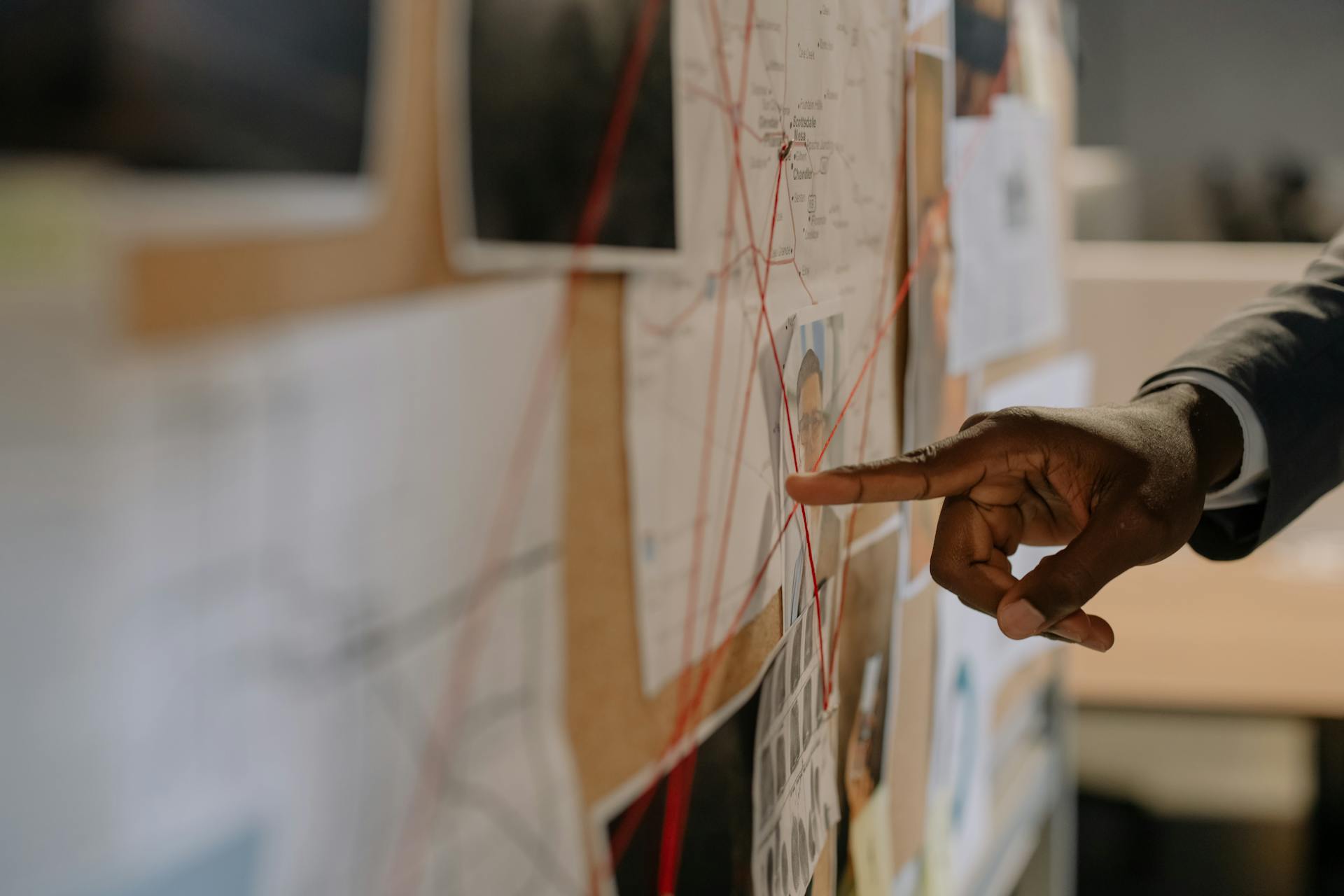 Close-Up Shot of a Person Pointing at Evidence Board