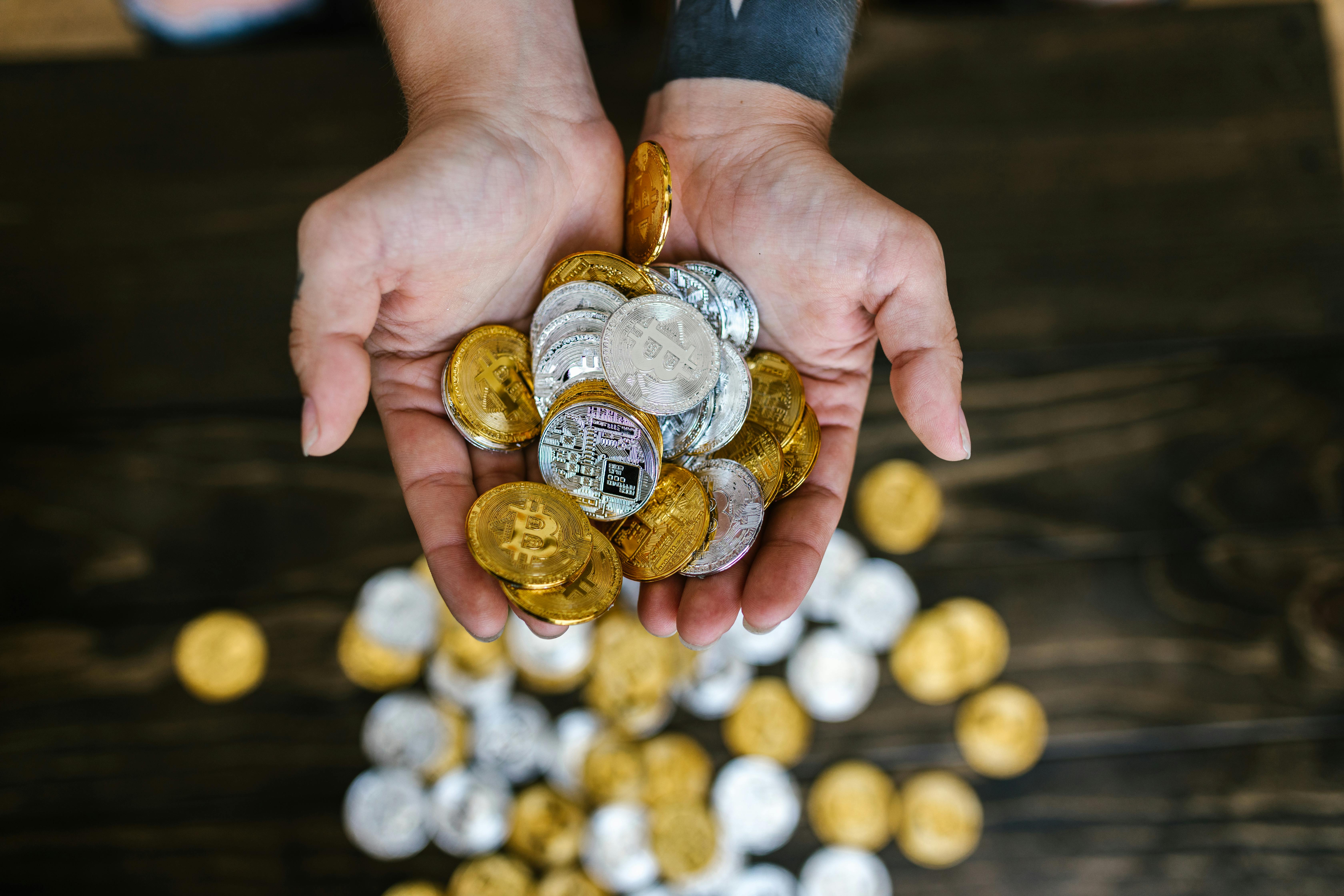 close up shot of person holding gold and silver bitcoins