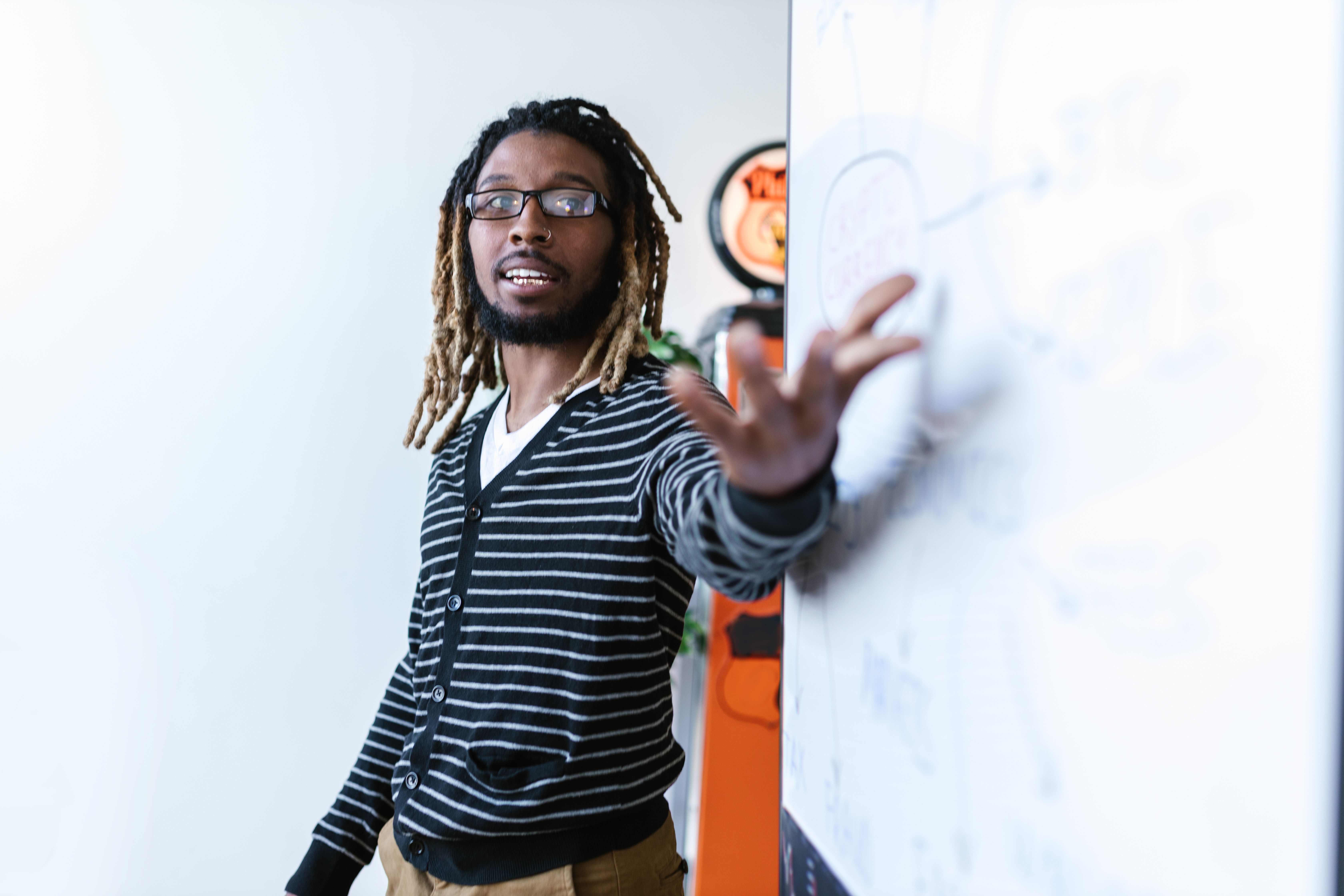 Jovem com dreadlocks fazendo uma apresentação em um ambiente de escritório moderno.