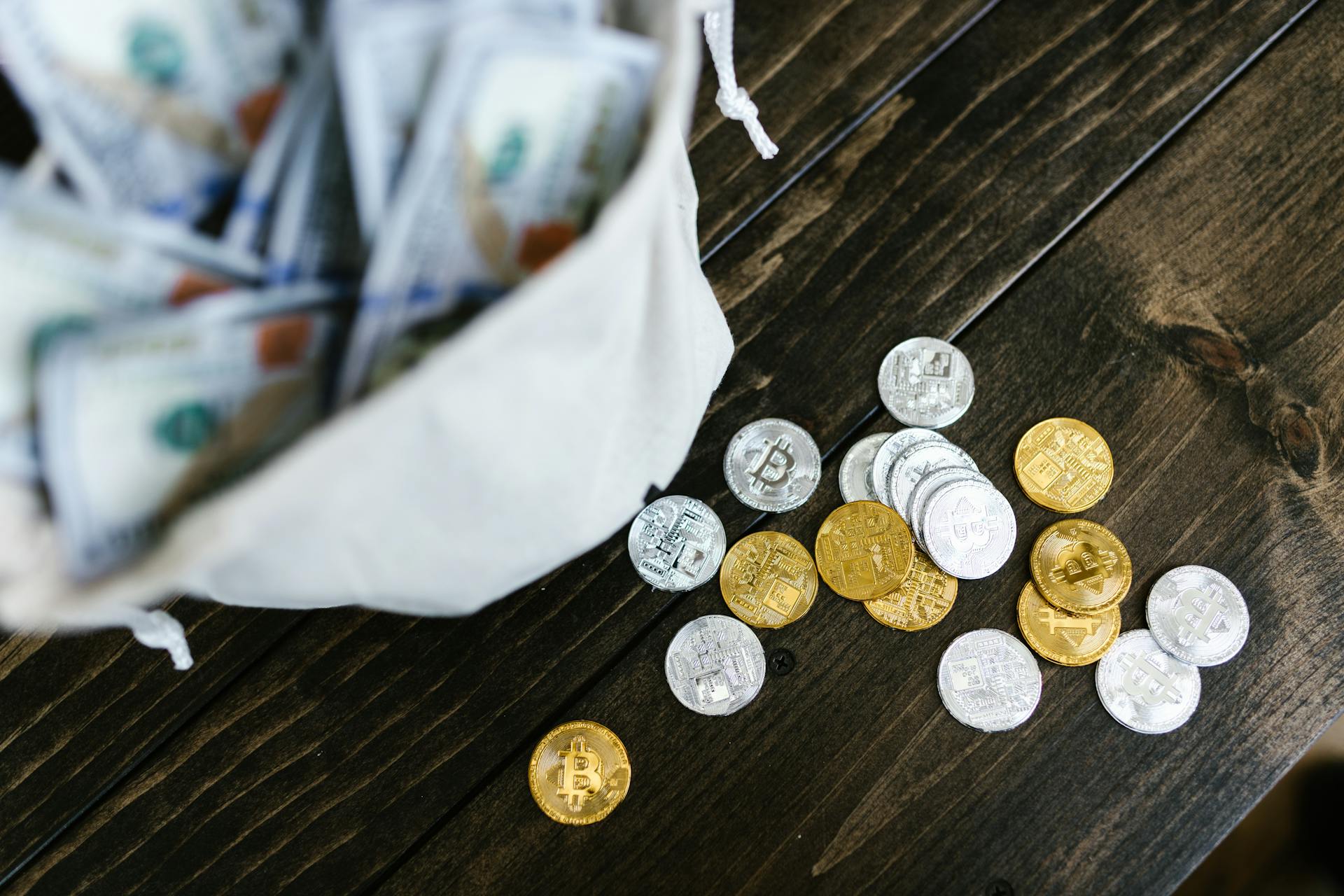 Close-Up Shot of Silver and Gold Bitcoins on Wooden Surface