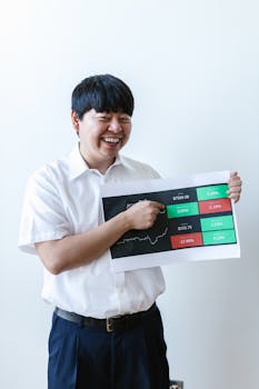 Smiling Asian man holding investment chart showcasing cryptocurrency trends and market changes.